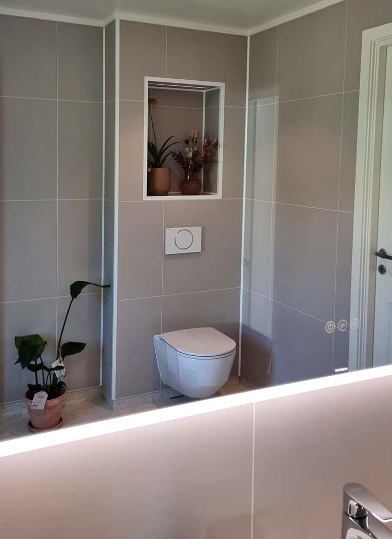 Speilbilde på det nye badet av nytt luktfritt toalett med lyse, delikate baderomsplater på veggene